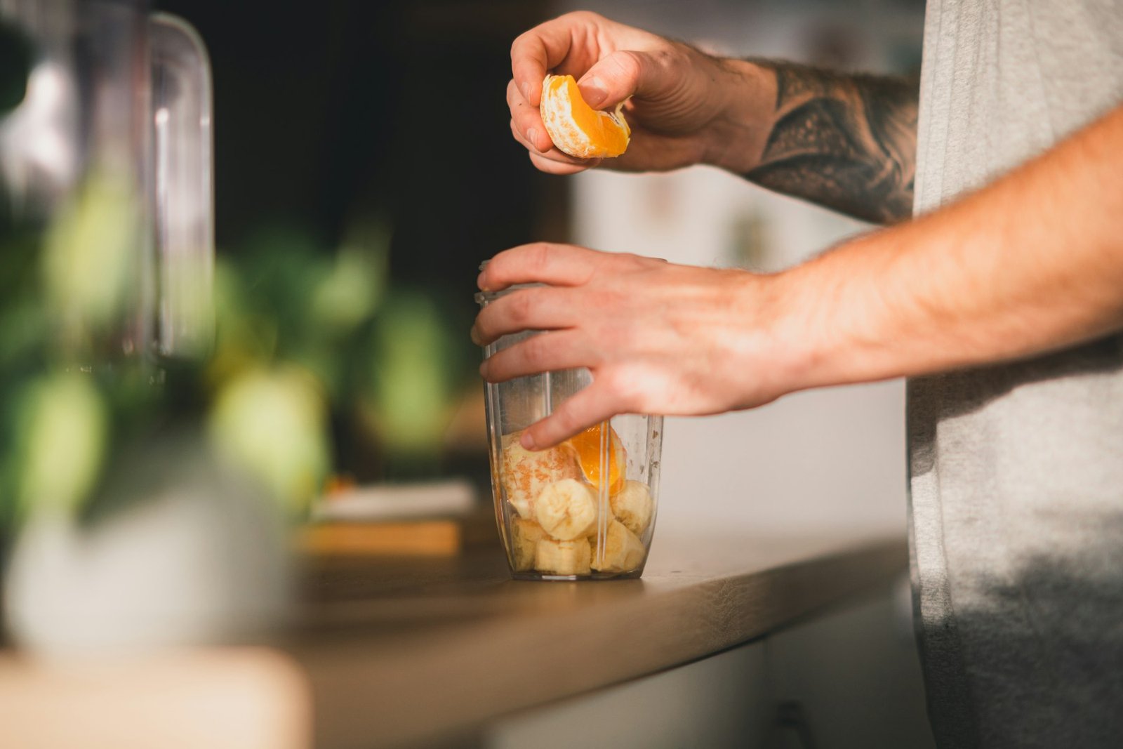 Persona preparando un batido de fruta en una batidora de vaso